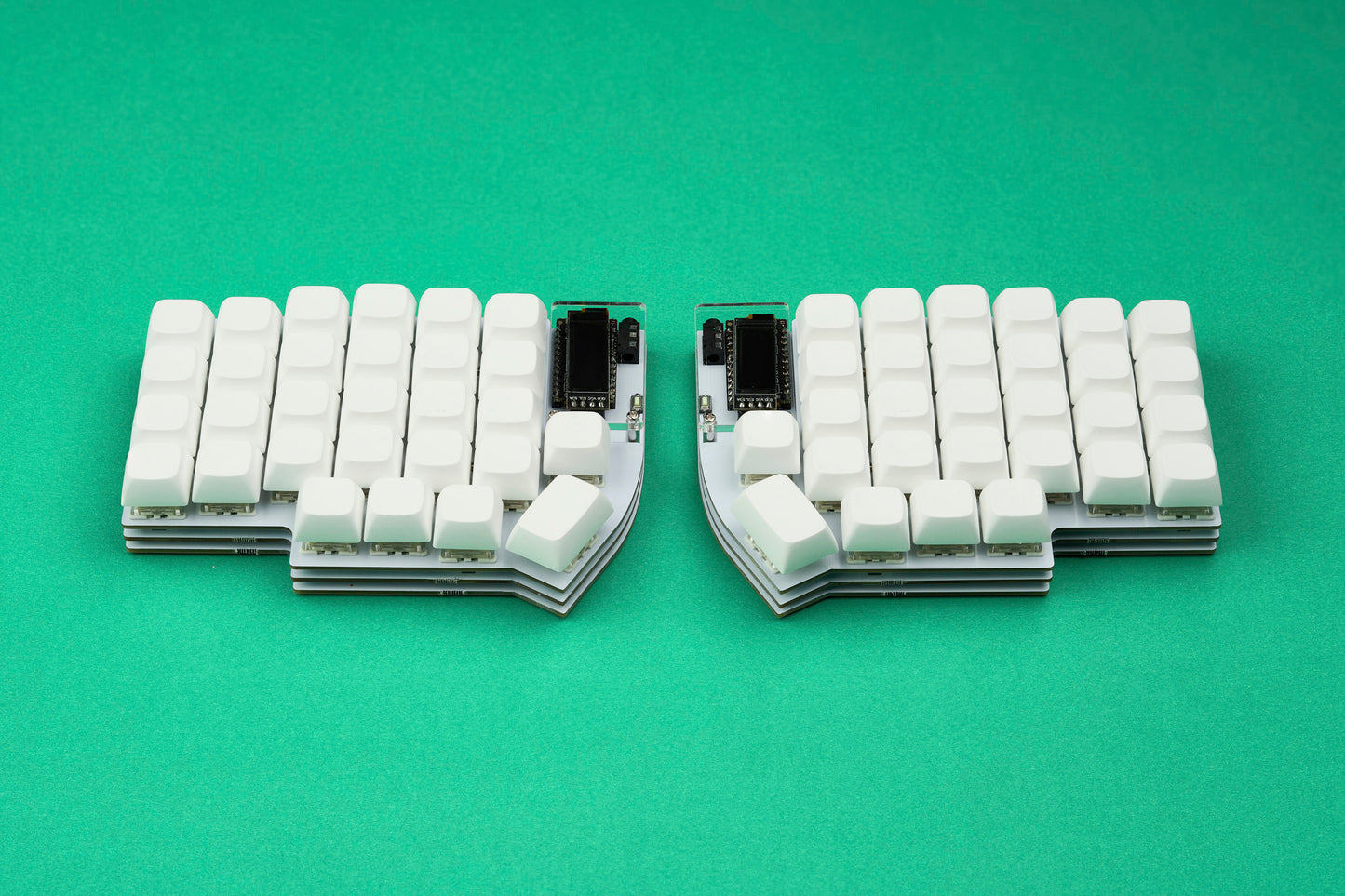 A white Lily58 keyboard with white keycaps shown from straight angle on top of a bright green backdrop.
