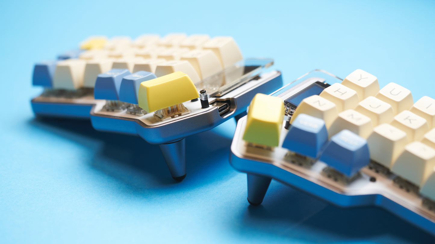 Gray Unicorne keyboard angled with yellow and blue keycaps and 10° tenting legs installed.
