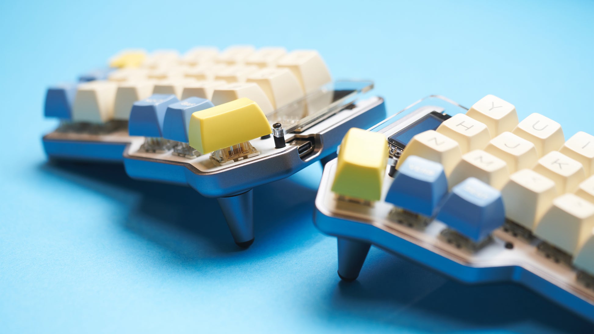 Gray Unicorne keyboard angled with yellow and blue keycaps and 10° tenting legs installed.