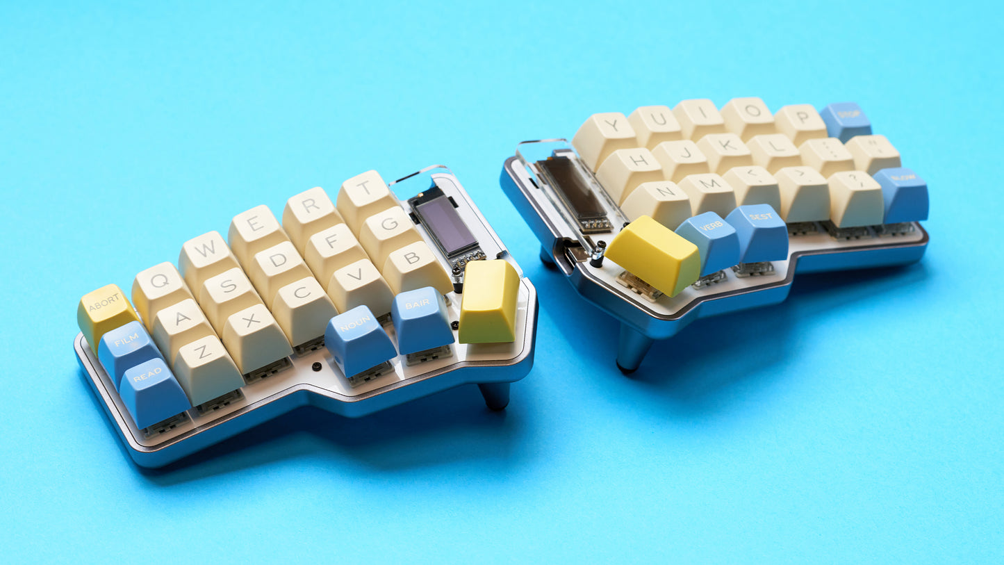 Unicorne keyboard build in silver with white, yellow, and blue keycaps shown tented from a side angle.