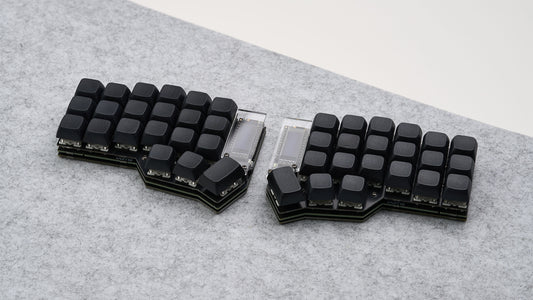 Corne DIY keyboard with all-black keycaps and OLED screens, assembled on gray felt deskmat.
